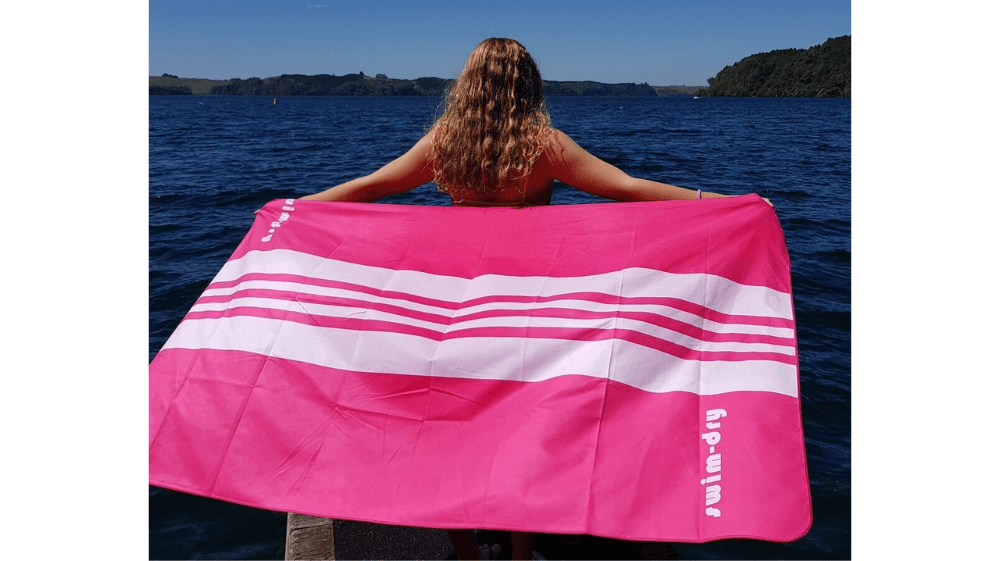 https://swimdryonline.com/wp-content/uploads/2023/07/Large-Beach-Towel-SeaBreeze-Curve-Pinkwhite-girl-on-beach.png